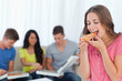 © WavebreakmediaMicro - A woman about to eat a slice of pizza with her friends behind he