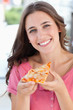 © WavebreakmediaMicro - Close up of a woman smiling with a piece of pizza and looking at