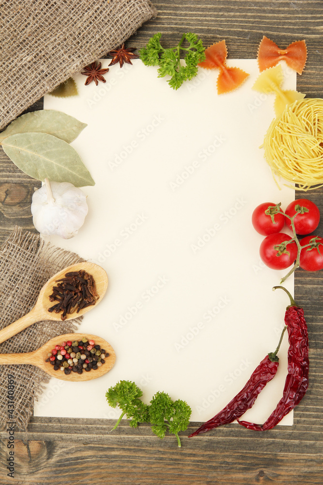 paper for recipes vegetables, and spices on wooden table