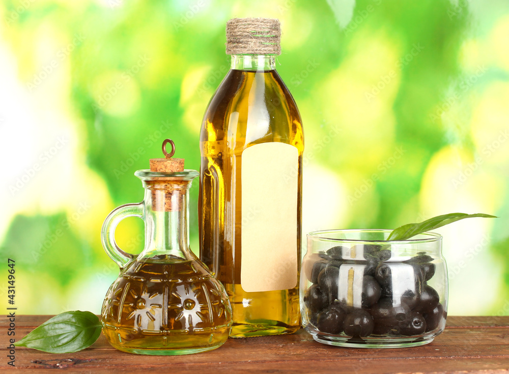 Olive oil bottle and small decanter on green background