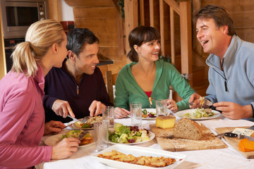 Group Of Friends Enjoying Meal In Alpine Chalet Together