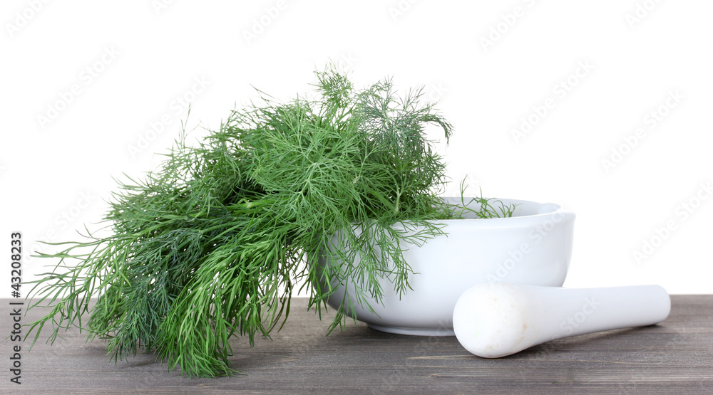 Dill in a mortar and pestle on wooden