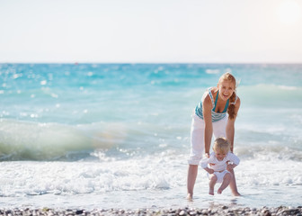 Wall Mural - Mother and baby playing with sea waves