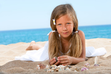 Sweet girl playing with shells on beach.