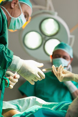 Surgeon taking a scalpel from a gloved hand