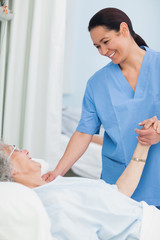 Wall Mural - Nurse smiling to a patient while holding her hand