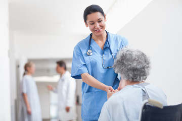 Wall Mural - Nurse standing next to a patient while holding her hands