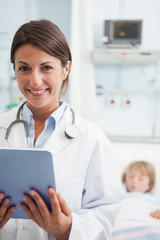 Wall Mural - Smiling doctor holding a tablet computer