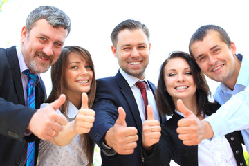 Successful young business people showing thumbs up sign