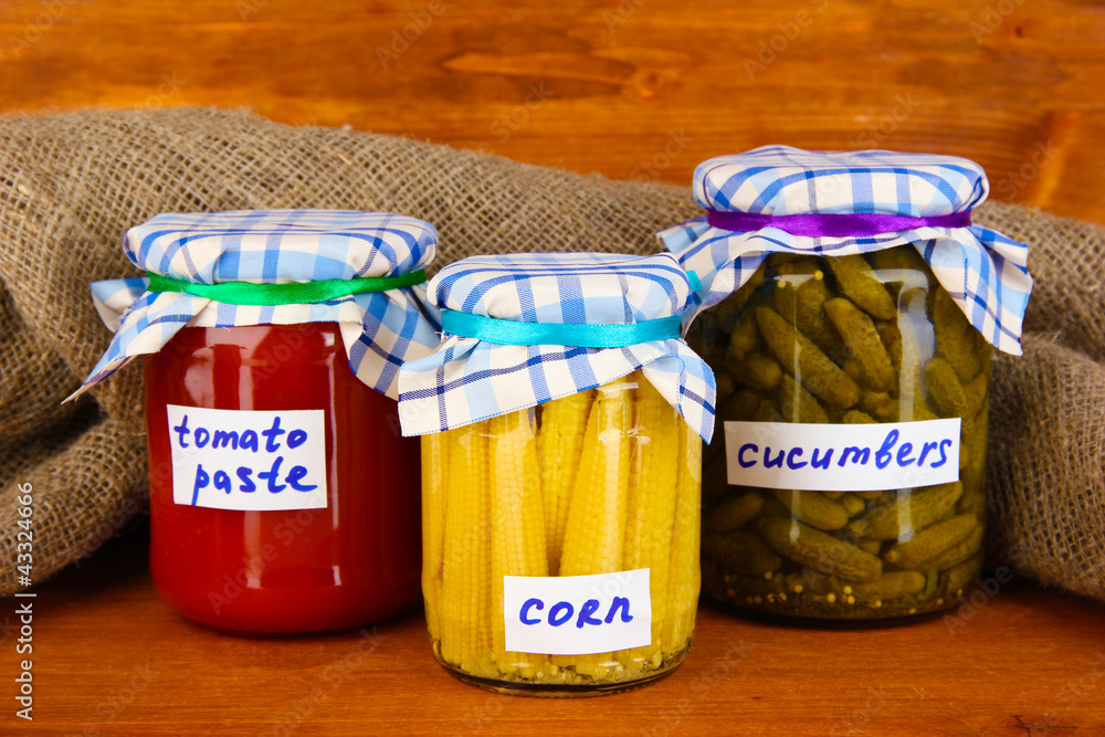 Jars with canned vegetables on wooden background close-up