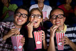 © Andres Rodriguez/Blend Images - Hispanic friends enjoying popcorn at movie theater