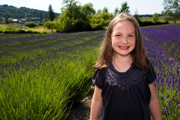 Wall Mural - Cute young girl in a field of purple lavender