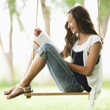 Caucasian Girl Reading Book On Swing