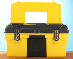 Wall Mural - Open yellow tool box on blue background close-up