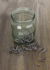 Wall Mural - Metal nails and glass jar on wooden background