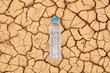 A water bottle on dry and cracked ground