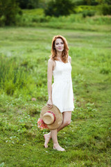 Wall Mural - Redhead girl at green grass at village outdoor.