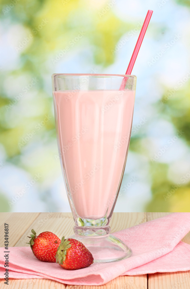 Strawberry milk shake on wooden table on bright background