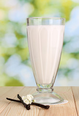 Wall Mural - Vanilla milk shake on wooden table on bright background