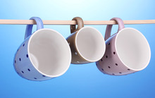 Nice Cups Hanging On Stick On Blue Background