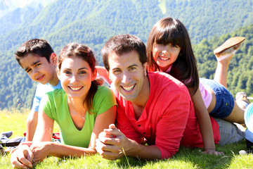 Wall Mural - Portrait of happy family laying on the grass in mountain