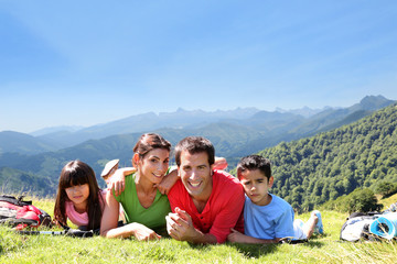 Wall Mural - Portrait of happy family laying on the grass in mountain