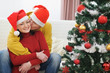© Alliance - Young man kissing girlfriend near Christmas tree