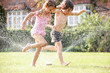 Two Children Running Through Garden Sprinkler