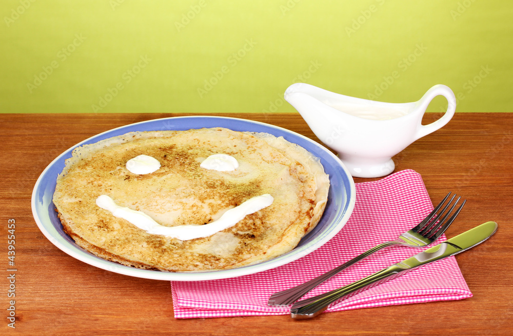 Stack of tasty pancakes on wooden table on green background