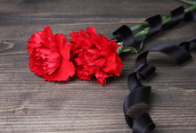 Carnations And Black Ribbon On Grey Wooden Background