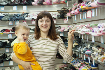 Wall Mural - Happy mother with child chooses baby shoes