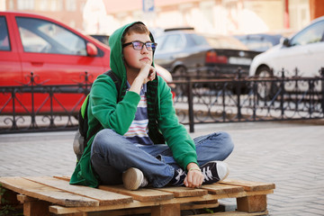 Young man sitting against a city traffic