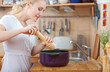 © listercz - young woman cooking in the kitchen- seasoning into a pot
