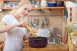 © listercz - young woman cooking in the kitchen- seasoning into a pot