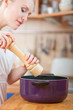 © listercz - young woman cooking in the kitchen- seasoning into a pot