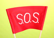 SOS signal written on red cloth on green background
