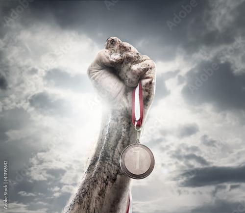 Naklejka na meble Male hand holding gold medal against the dramatic sky