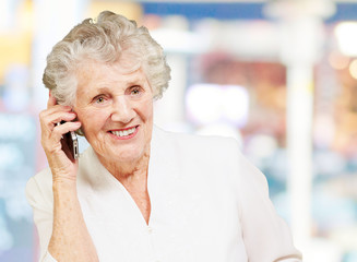 portrait of senior woman talking on mobile against a abstract ba