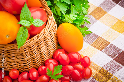 Tapeta ścienna Wiklinowy koszyk pełen świeżych pomidorów i pomidorów cherry