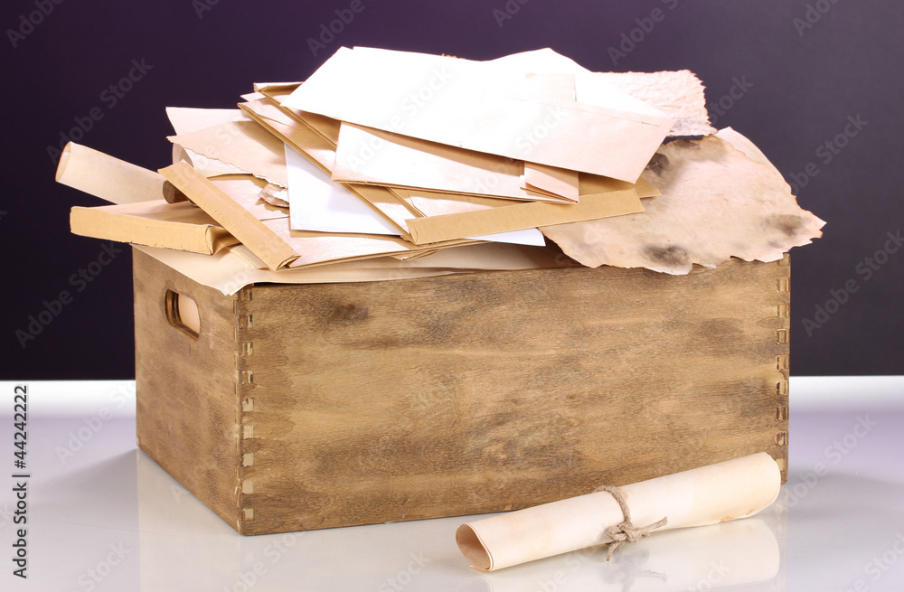 Wooden crate with papers and letters on purple background