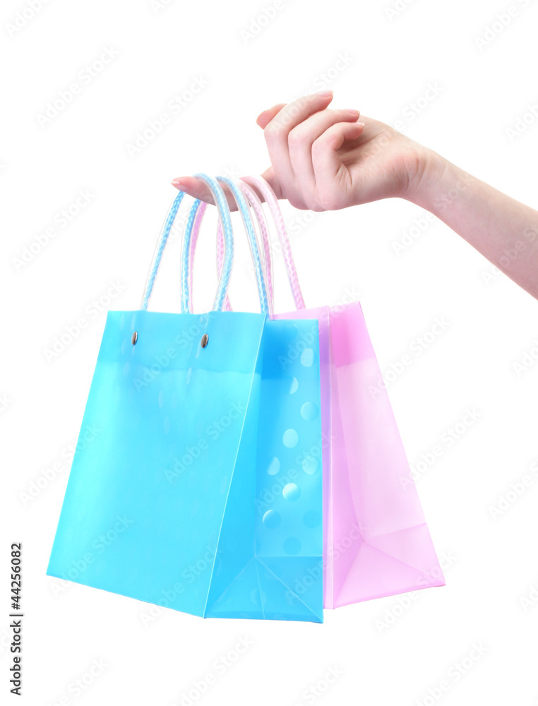 Female hand holding bright shopping bags isolated on white