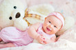 pretty smiling baby girl and teddy bear at the bed