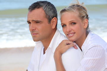 Couple dressed in white stood on beach