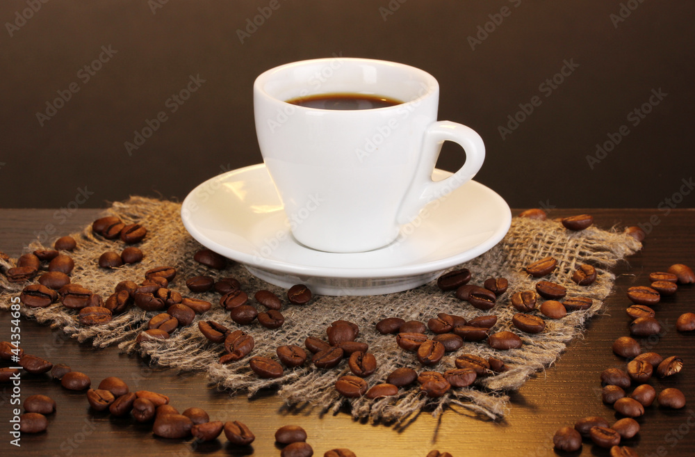 Cup of coffee on wooden table on brown background