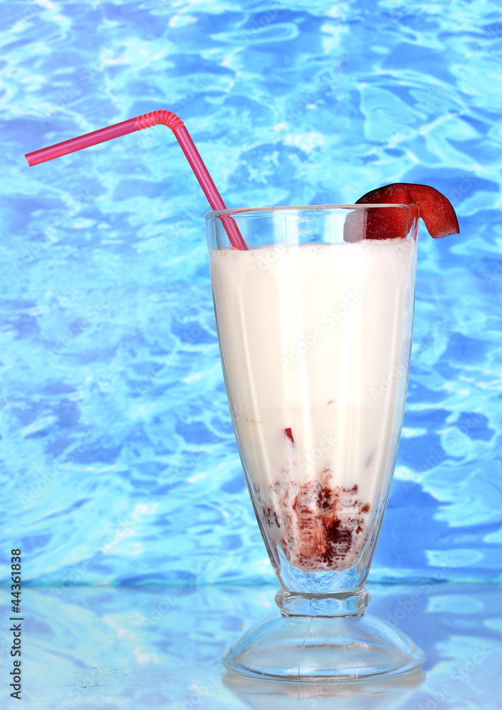 Delicious milk shake with fruit on table on blue sea background