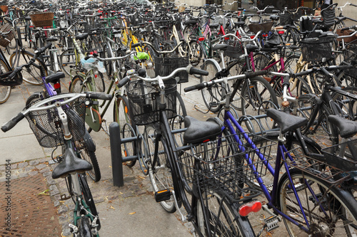 Photo Many different bicycles with baskets are parked in cycle parking