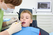 © Pavel Losevsky - Dentist in mask looks at teeth of little boy in dental clinic