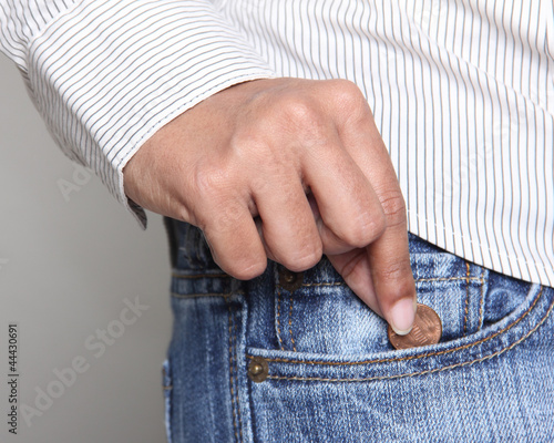 Fotomural person taking a penny from jean pocket