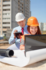 Two architects works in front of building site