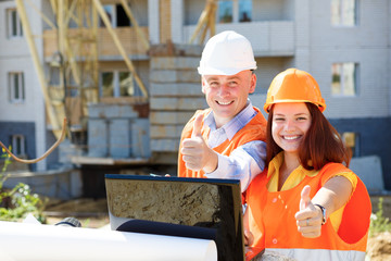 female and male construction workers looking at laptop and smili